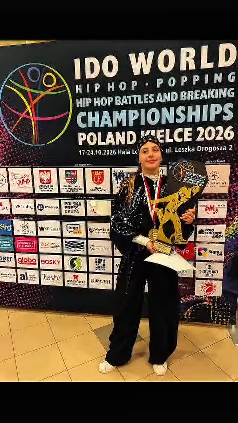 Uczennica SP nr 1 w Olkuszu z medalem i pucharem na tle planszy mistrzostw świata IDO w Kielcach
